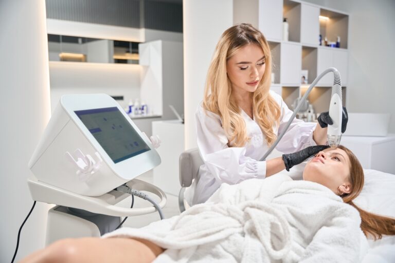 Kosmetička provádí mikrovpichové liftingové ošetření čela ženy v profesionálním salonu.